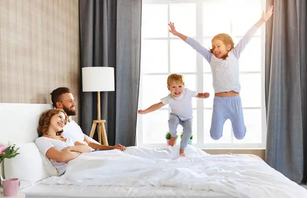 happy family jumping in bed