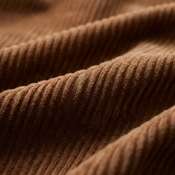 Close-up of brown cotton corduroy fabric showing parallel raised wales and a soft cut-pile surface
