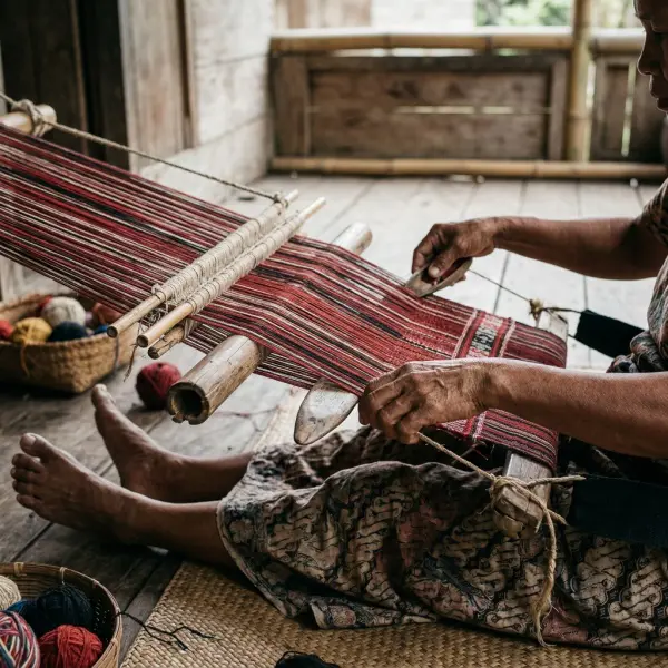 Penenun mengerjakan kain ulos Batak Toba dengan alat tenun tradisional Penenun mengerjakan kain ulos Batak Toba dengan alat tenun tradisional