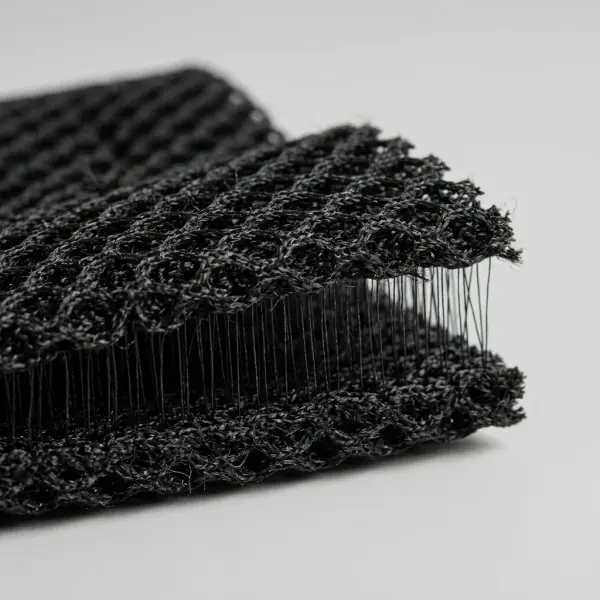 Close-up side view of black three-dimensional spacer mesh showing two knitted surfaces connected by spacer yarns Close-up side view of black three-dimensional spacer mesh showing two knitted surfaces connected by spacer yarns