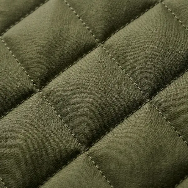 Detailed close-up of diamond-quilted textile showing raised fabric sections, precise stitching, and dimensional surface texture