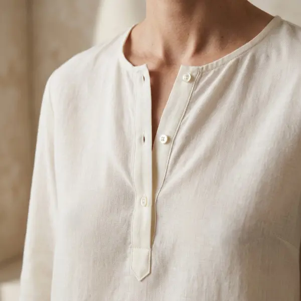 Lightweight woven blouse featuring a short neckline placket with small buttons and a clean finished opening