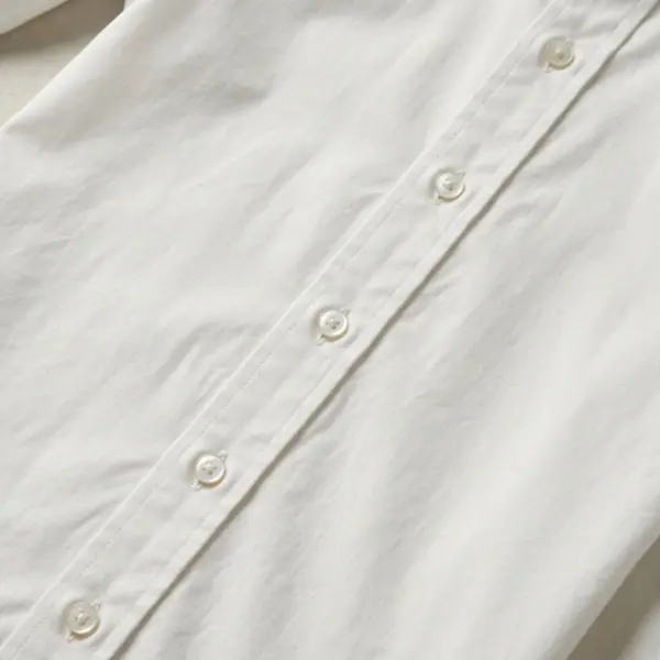 Close-up of a white cotton shirt showing a traditional visible button placket with evenly aligned buttons and topstitching Close-up of a white cotton shirt showing a traditional visible button placket with evenly aligned buttons and topstitching